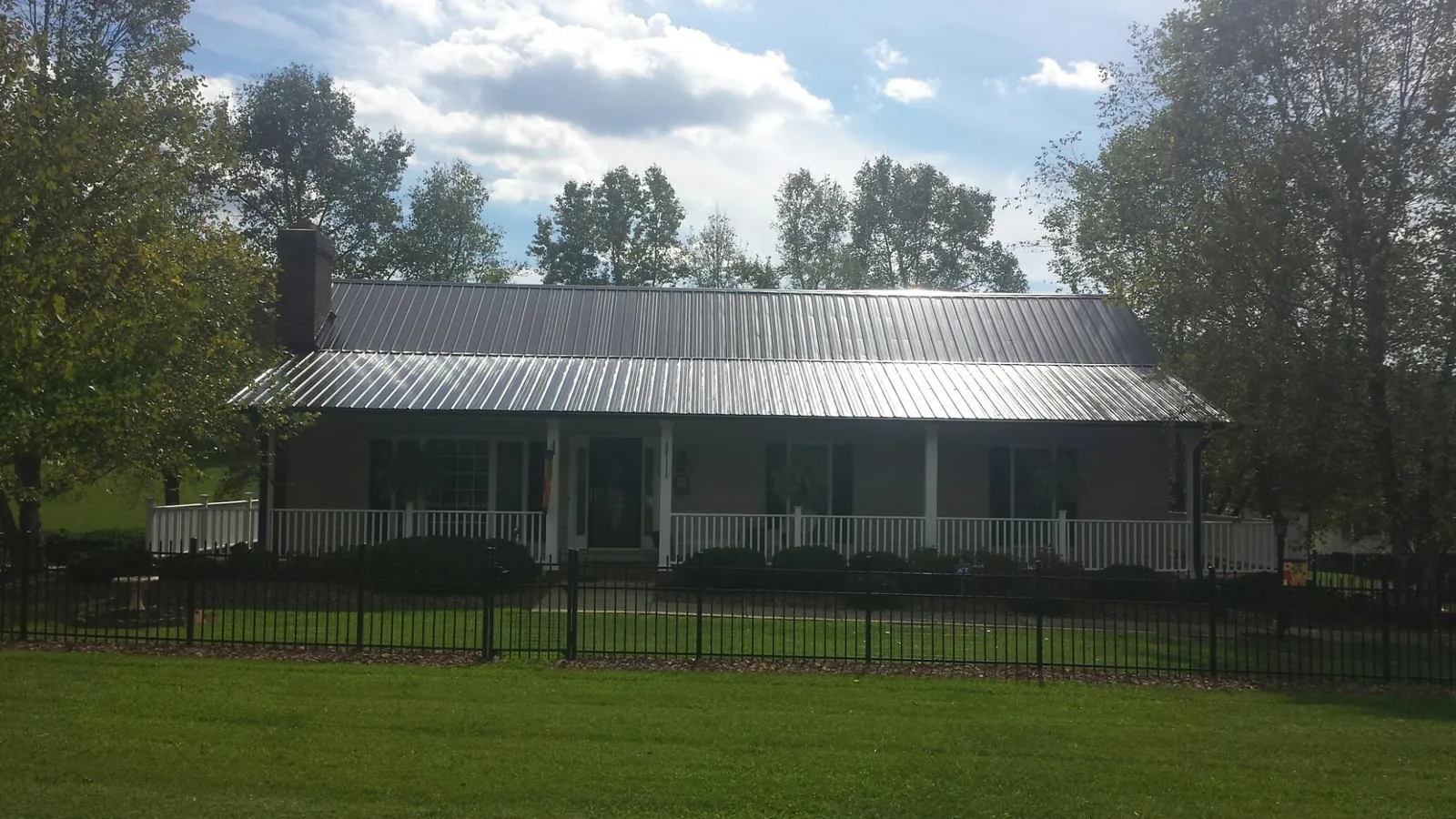 Gray metal roof on a brick ranch with a full width front porch — Gutter Guard Installation work by our crew in Waynesburg